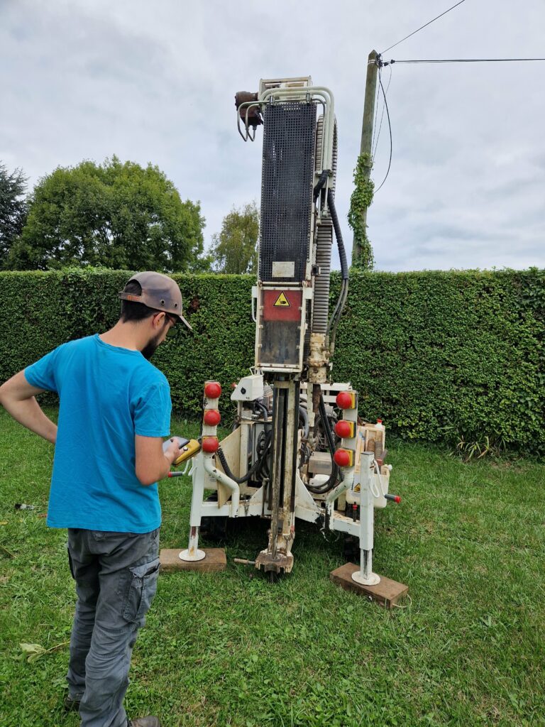 Forage géotechnique en cours pour l’analyse du sol avant la construction d’une maison. Étape essentielle pour assurer la solidité des fondations dans le cadre de la garantie constructeur.