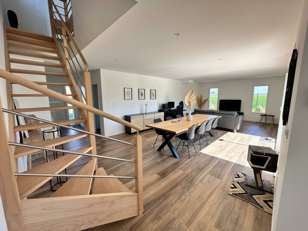 Vue sur la salle à manger et les escaliers menant à l'étage d'une maisons neuve et aménagée.